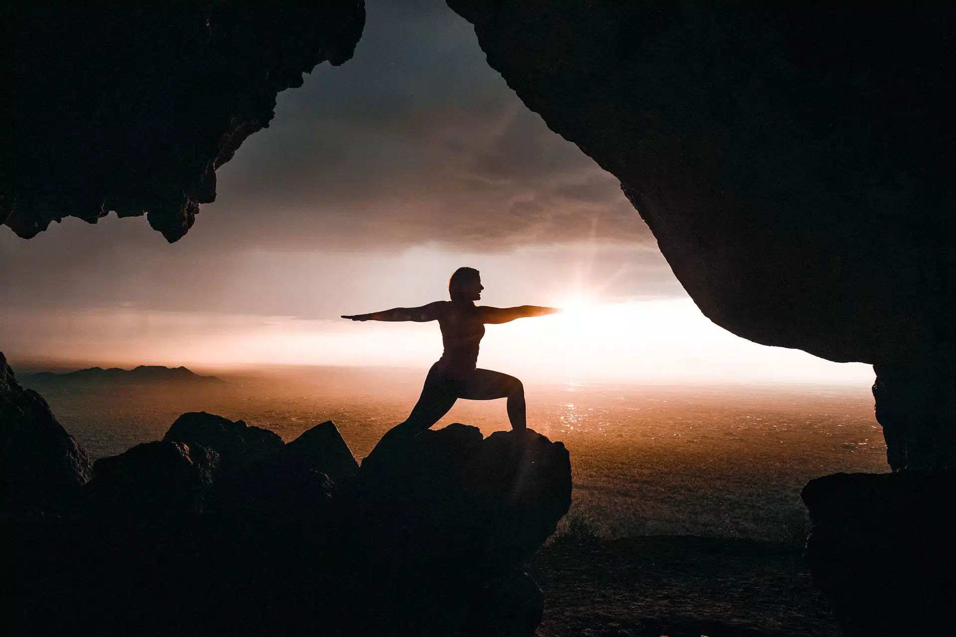 A person doing Warrior II pose on rocks
