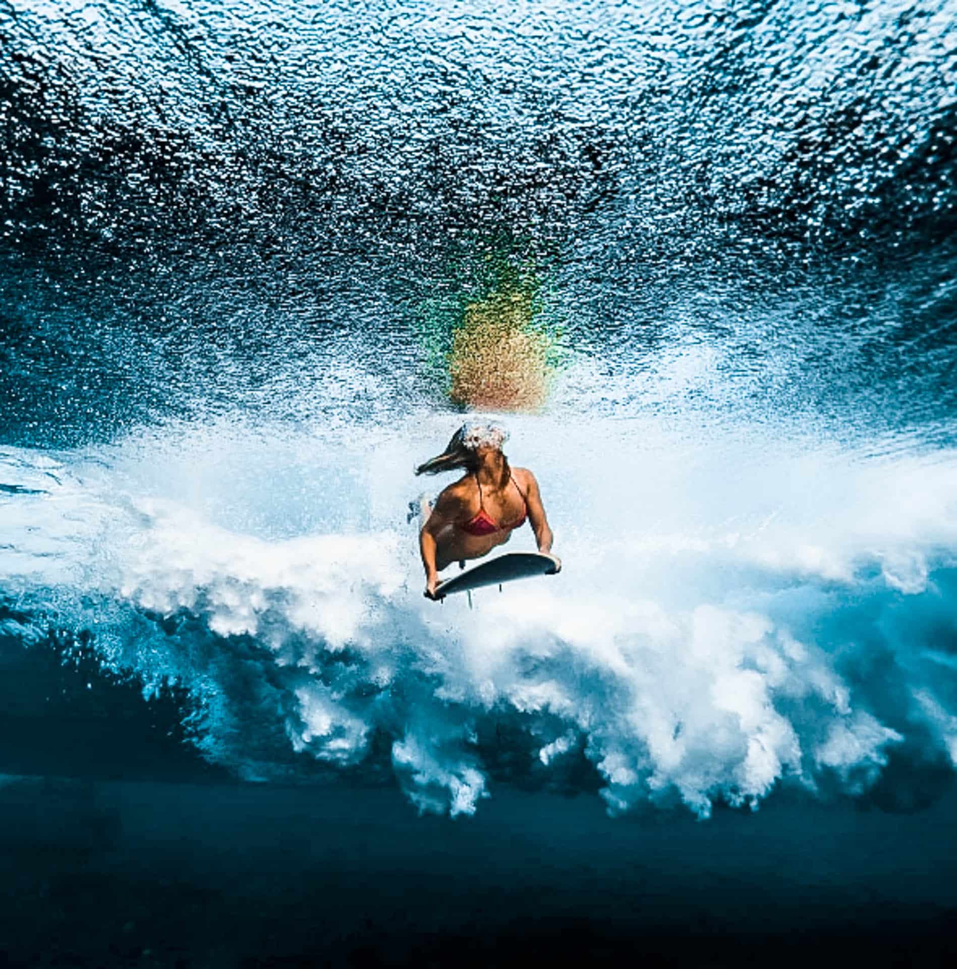 Surfer inside the ocean with their surfboard.