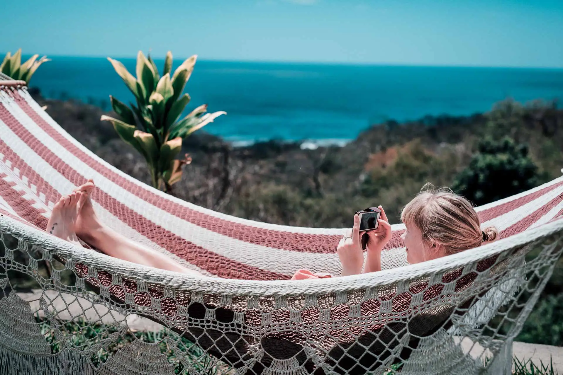 Girl in the Hamock checking the latest news on here phone Rapture Surfcamp Nicaragua