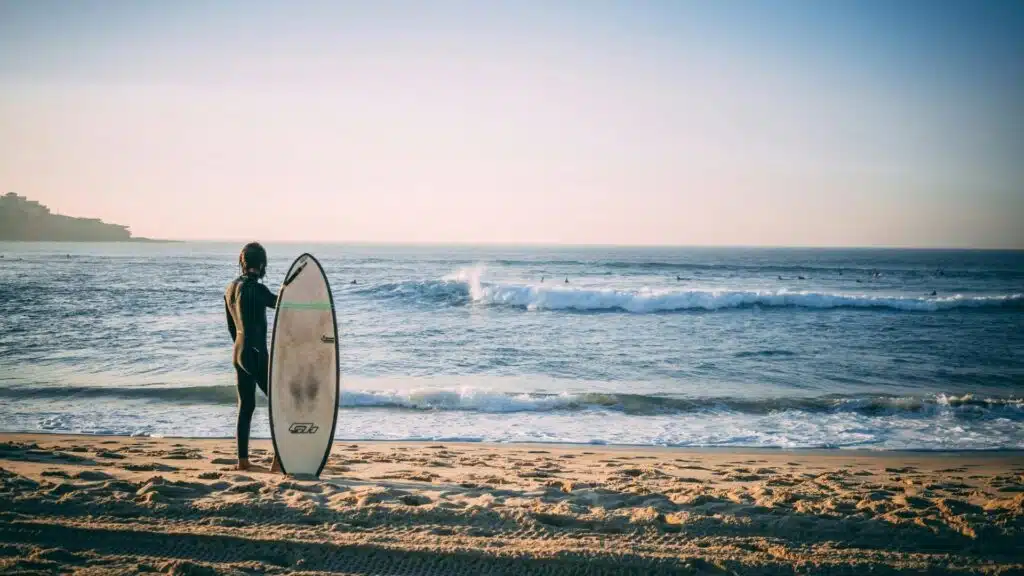 A surfer holding a surfboard looking out to sea