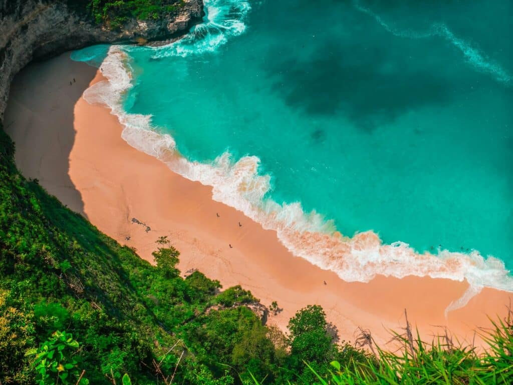 An overhead shot of a beach in Bali, Indonesia consiting of gold sand and bright blue water