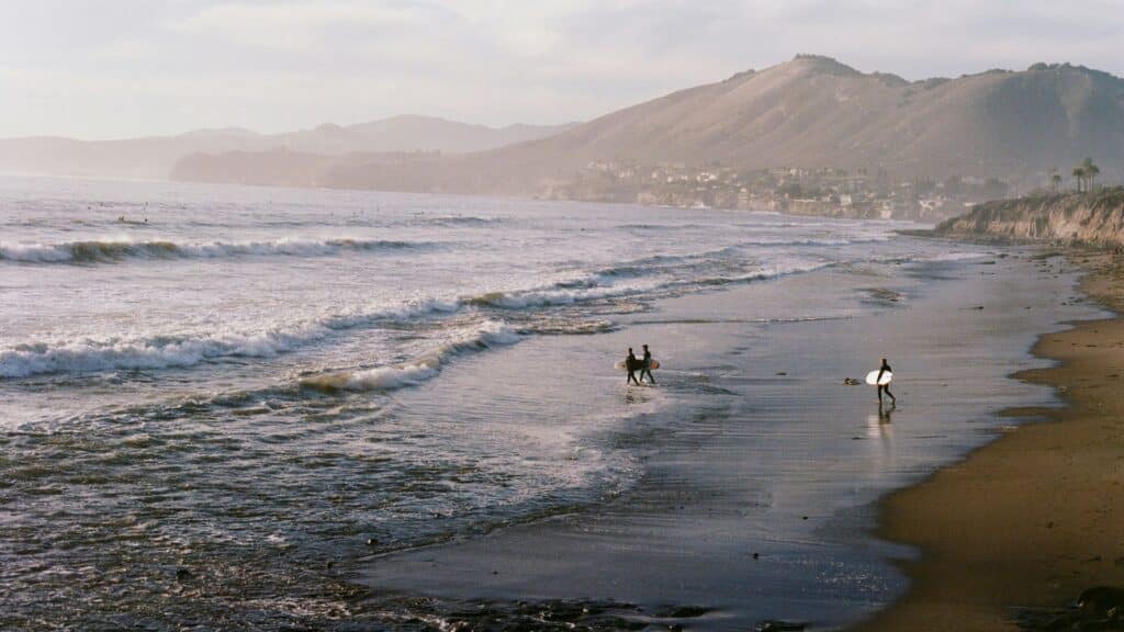 An image of surfers entering the sea and the tide is low