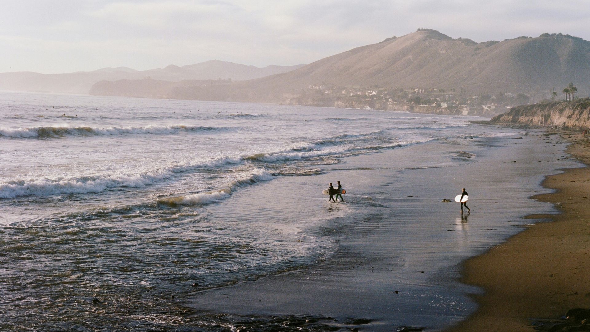 An image of surfers entering the sea and the tide is low