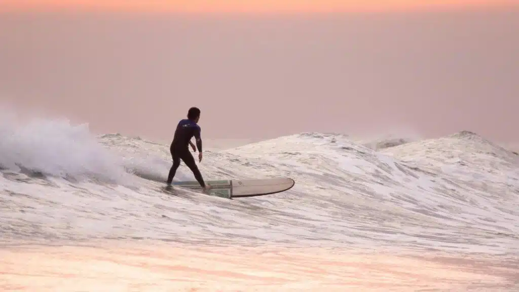 An image of a surfer riding a longboard he has the perfect stance of right foot in front of left chest side on and knees slightly bent 