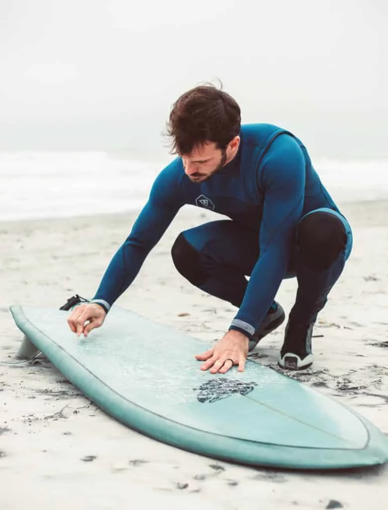 Man putting wax on his surfboard