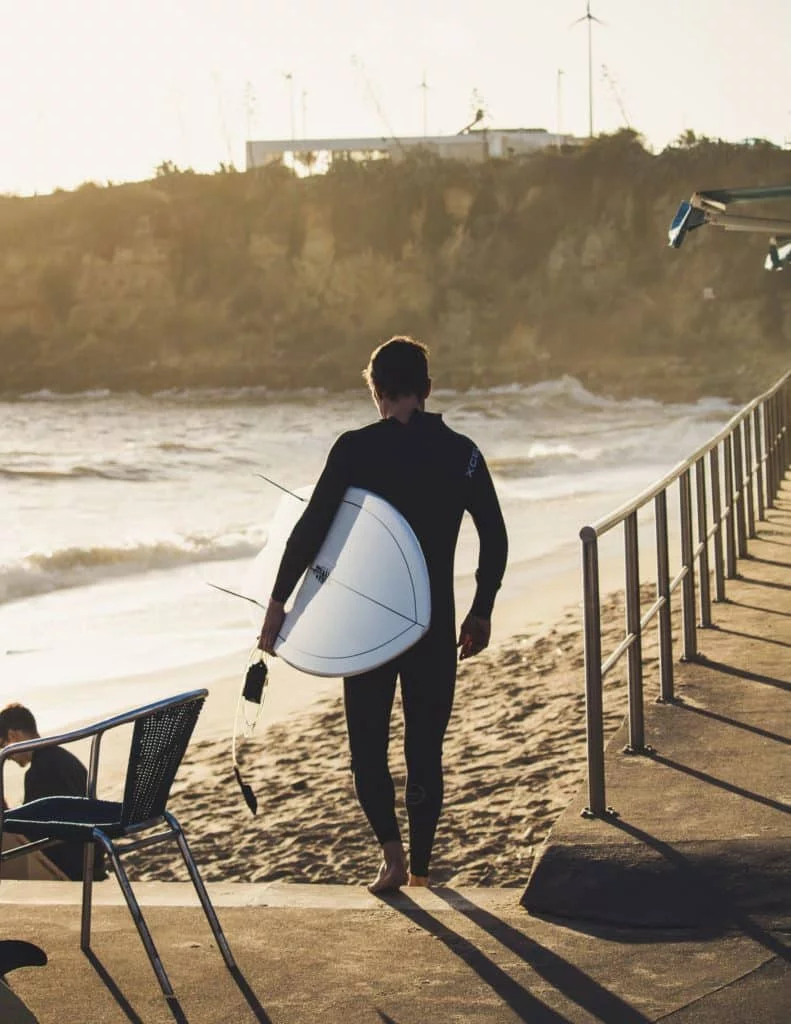 Man with a surfboard walking down the beach