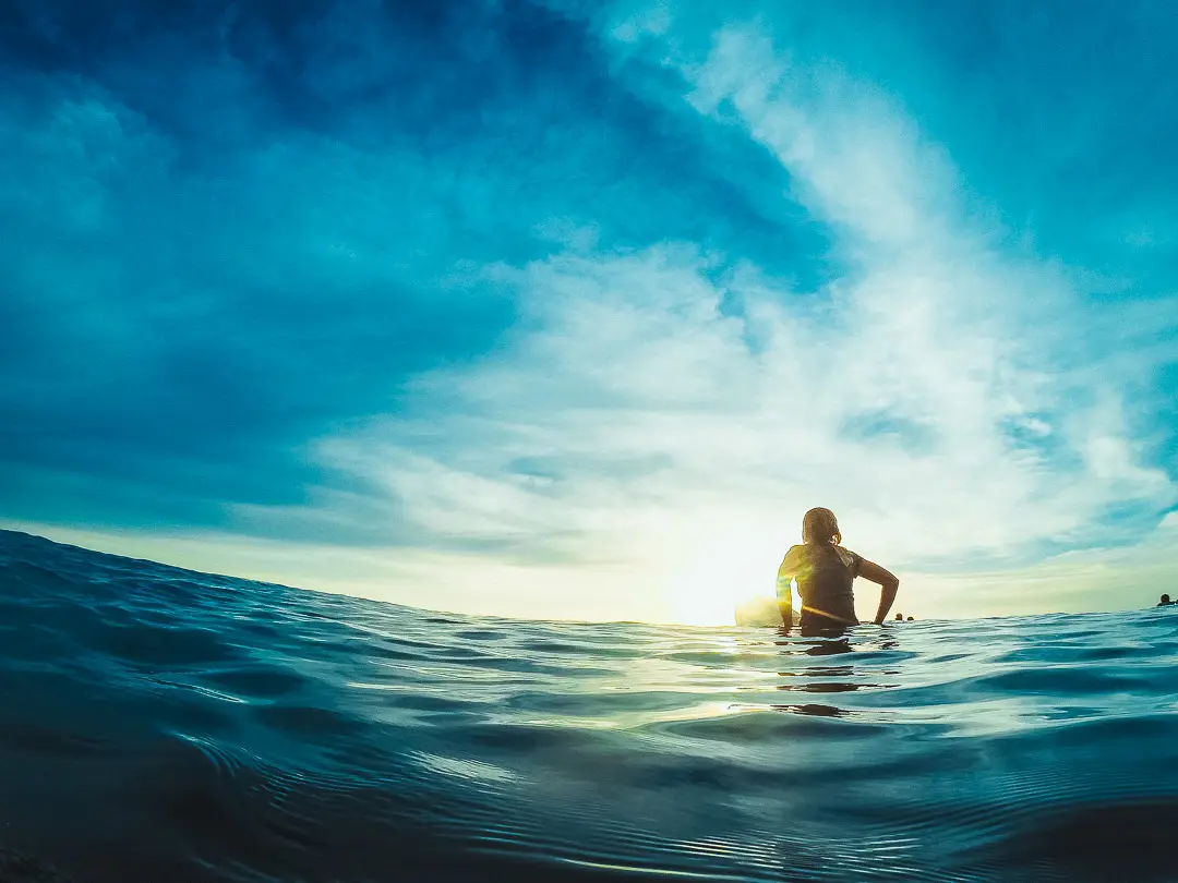 A girl sitting on surfboard waiting for wave