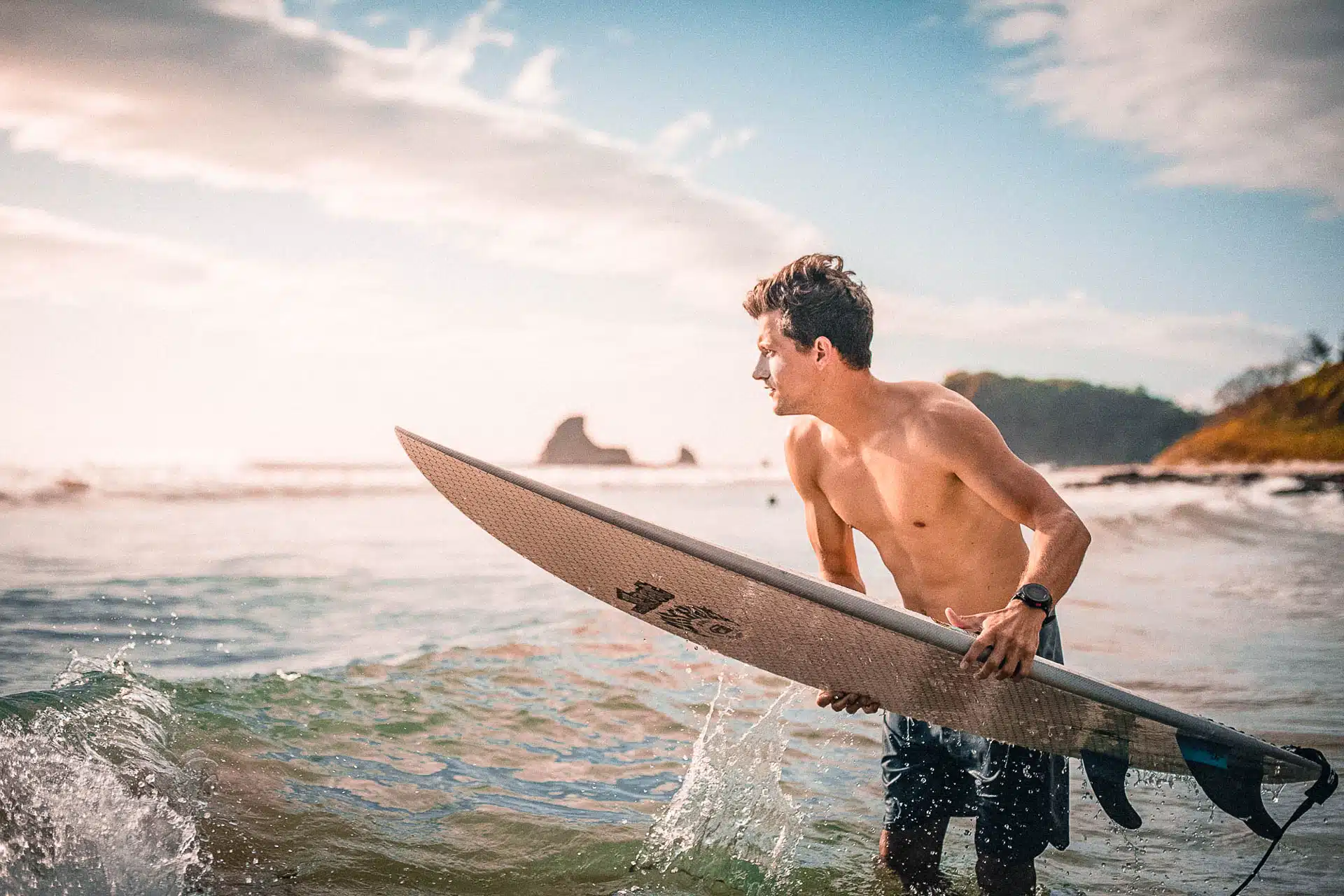 A person with surfboard standing with their surf board over the ocean.
