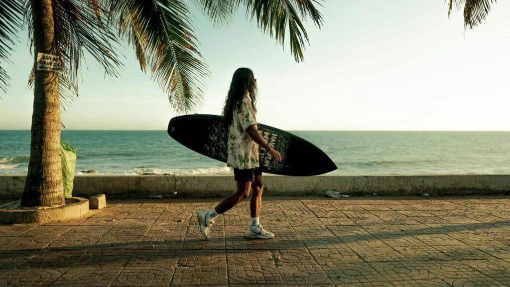 Ein Bild einer Person, die mit einem Surfbrett am Strand entlanggeht