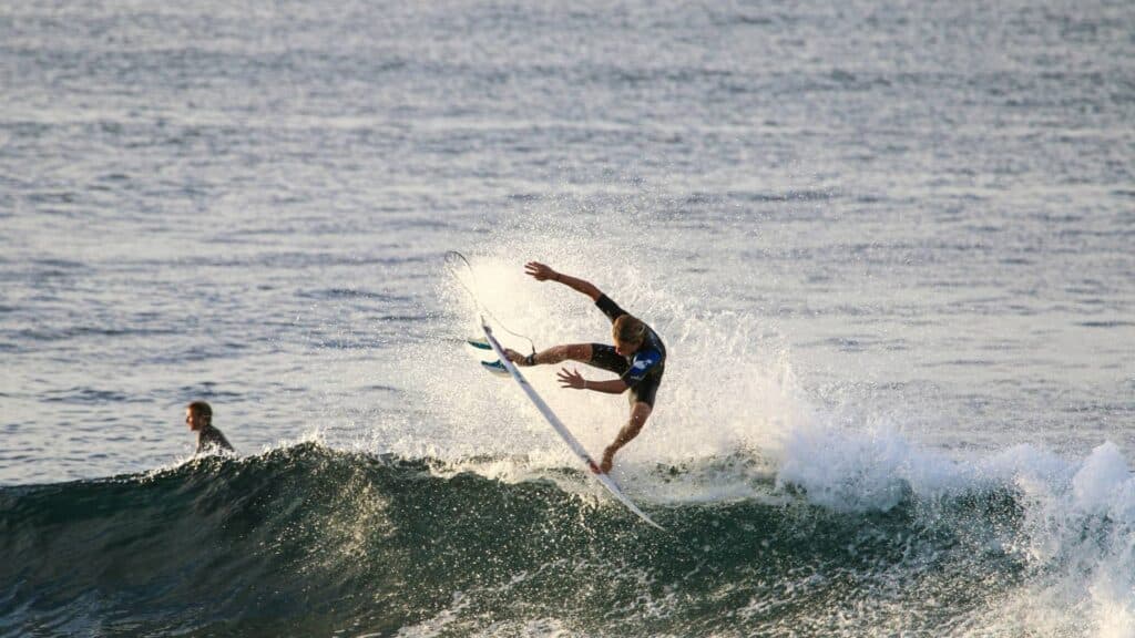 An image of Professional surfer Eno James throwing his fins in the air