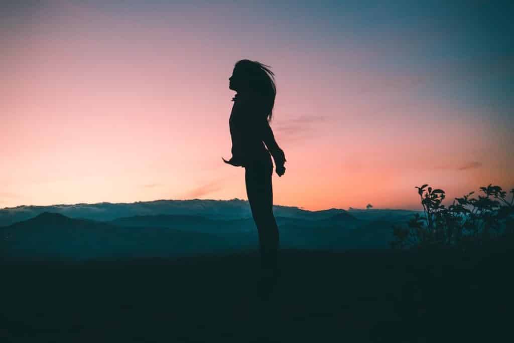 Girl in backlight breathing on the top of a mountain in Costa Rica