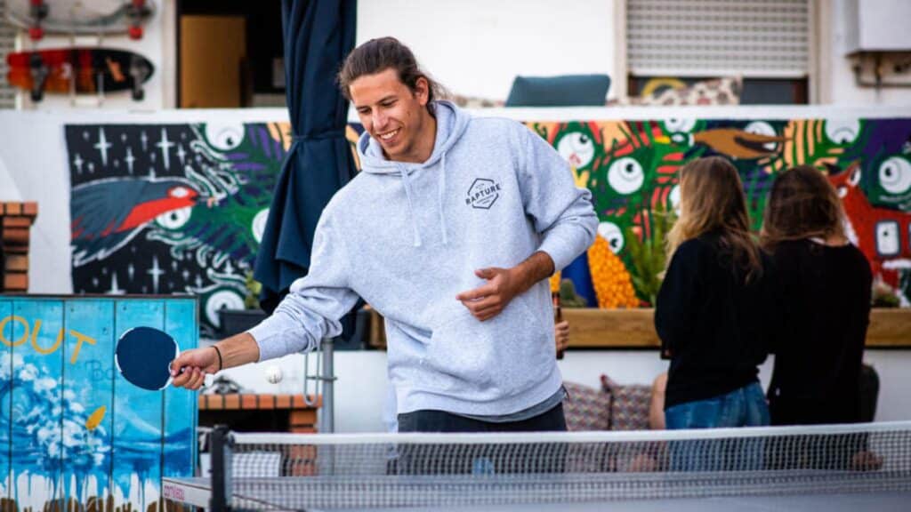 An image of a man playing table tennis in a grey jumper