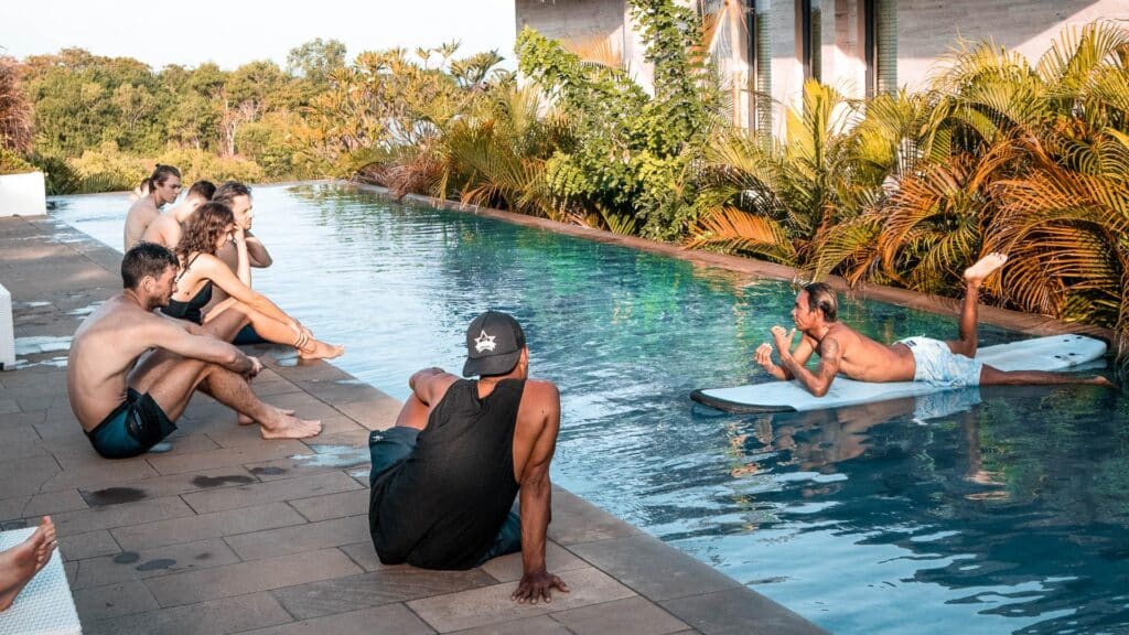 An image of a man on a surfboard speaking to guests at rapture surfcamps