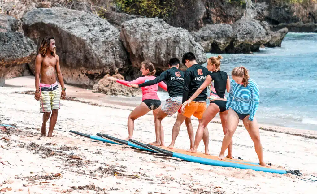 An image of surfers practicing surf techniques on a beach in Bali
