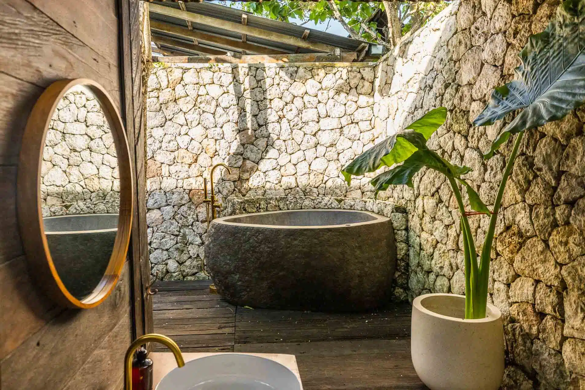 A Balinese outside bathroom finished with stones and natural fixtures.