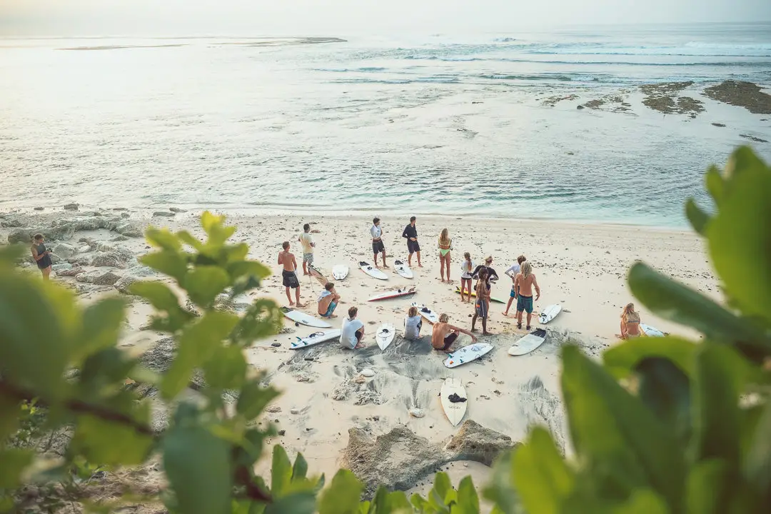 Eine Gruppe von Surfern, die sich für den Surf Unterricht aufwärmen