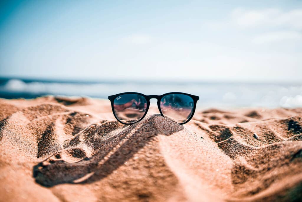 An image of sunglasses on a beach