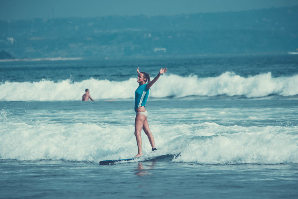 A girl surfing at the beach in wetsuit