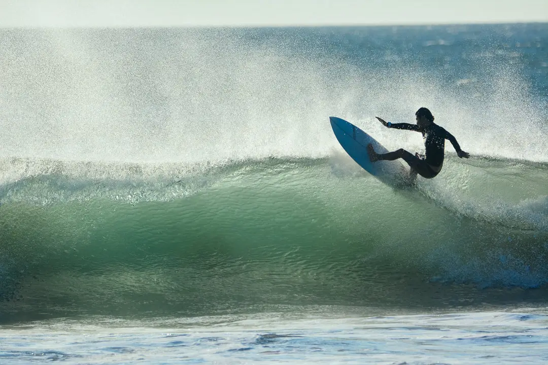 A surfer riding a small wave at ocean