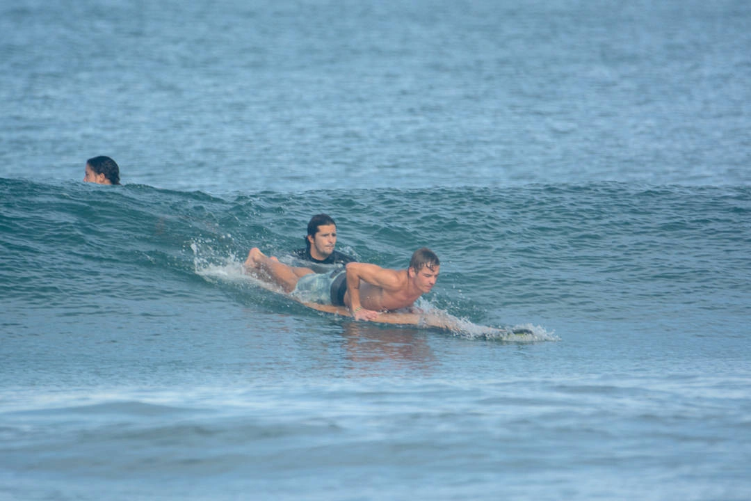 A group of surfers jumping with surfboards