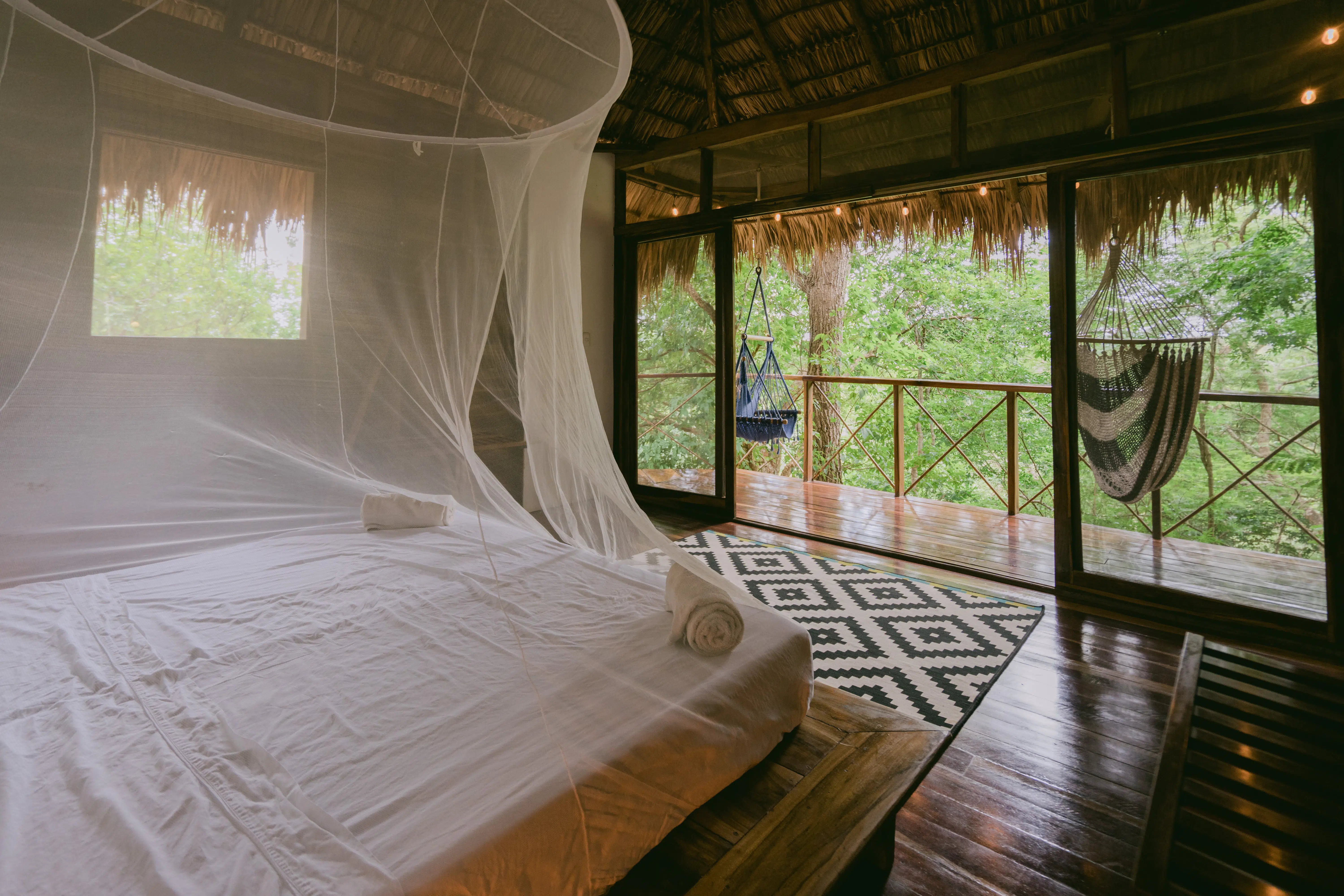 A bed with mosquito net on the cabana room in Rapture Surf resort