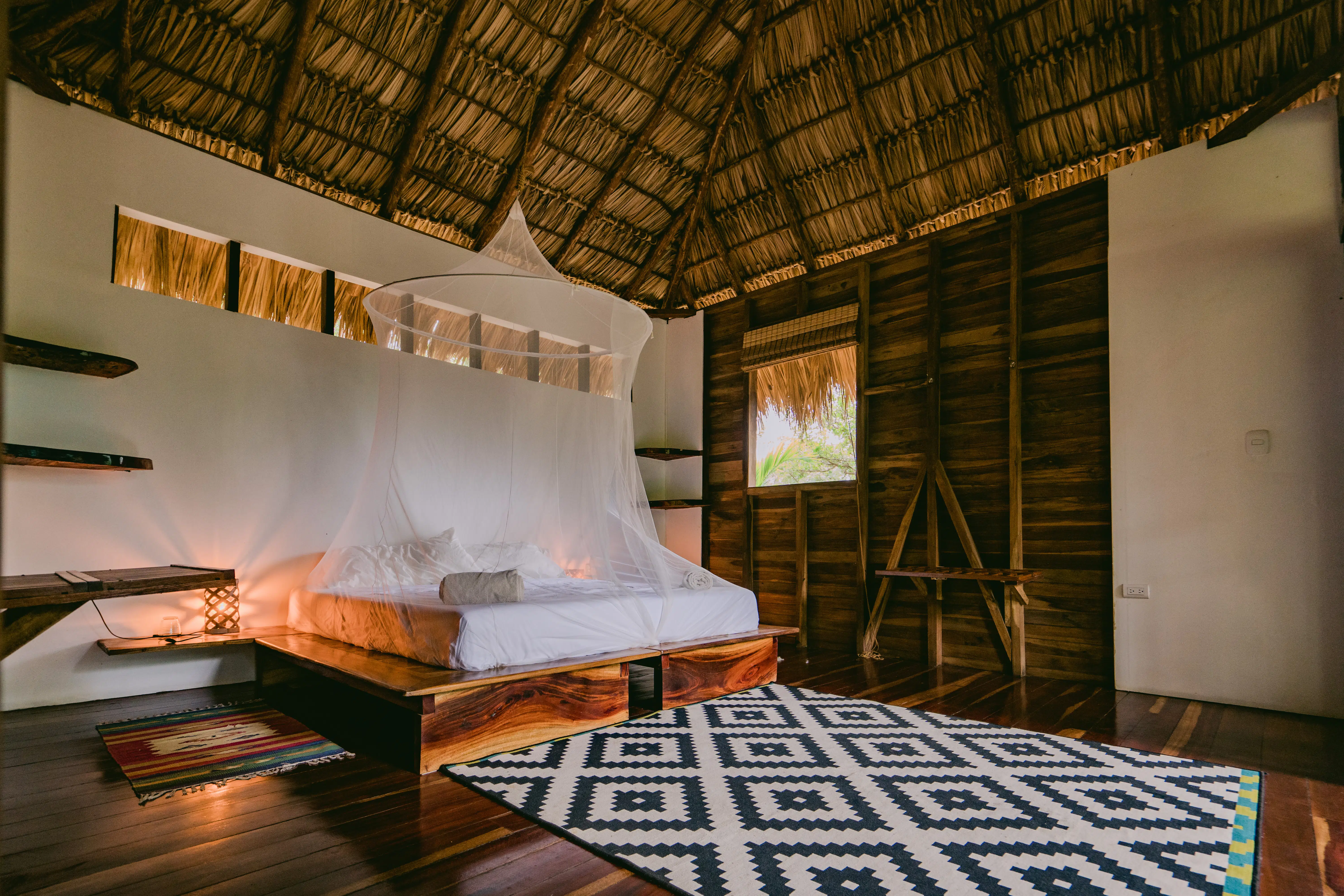 A bed with mosquito net on the cabana room in Rapture Surf resort