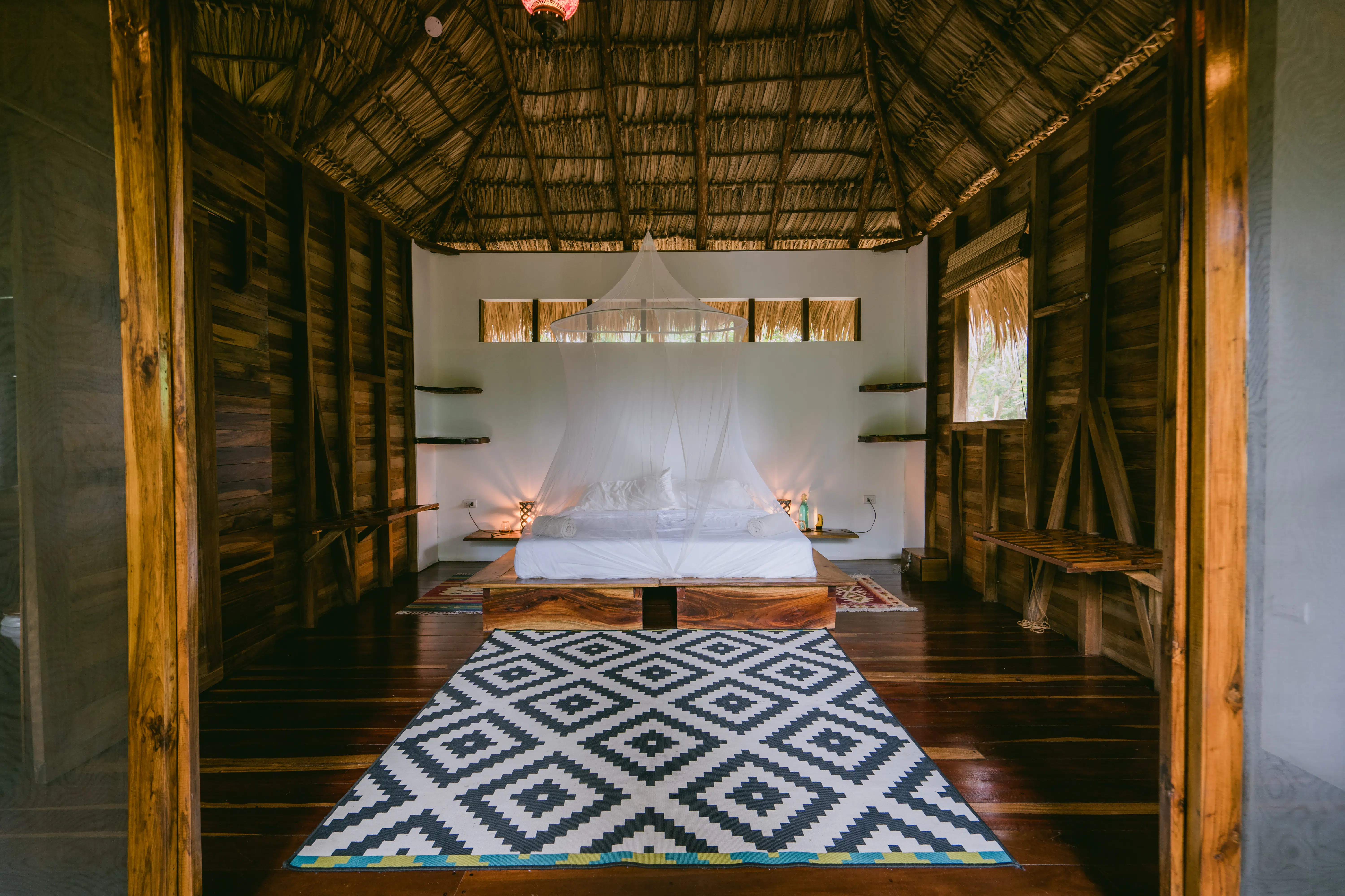 A bed with mosquito net on the cabana room in Rapture Surf resort