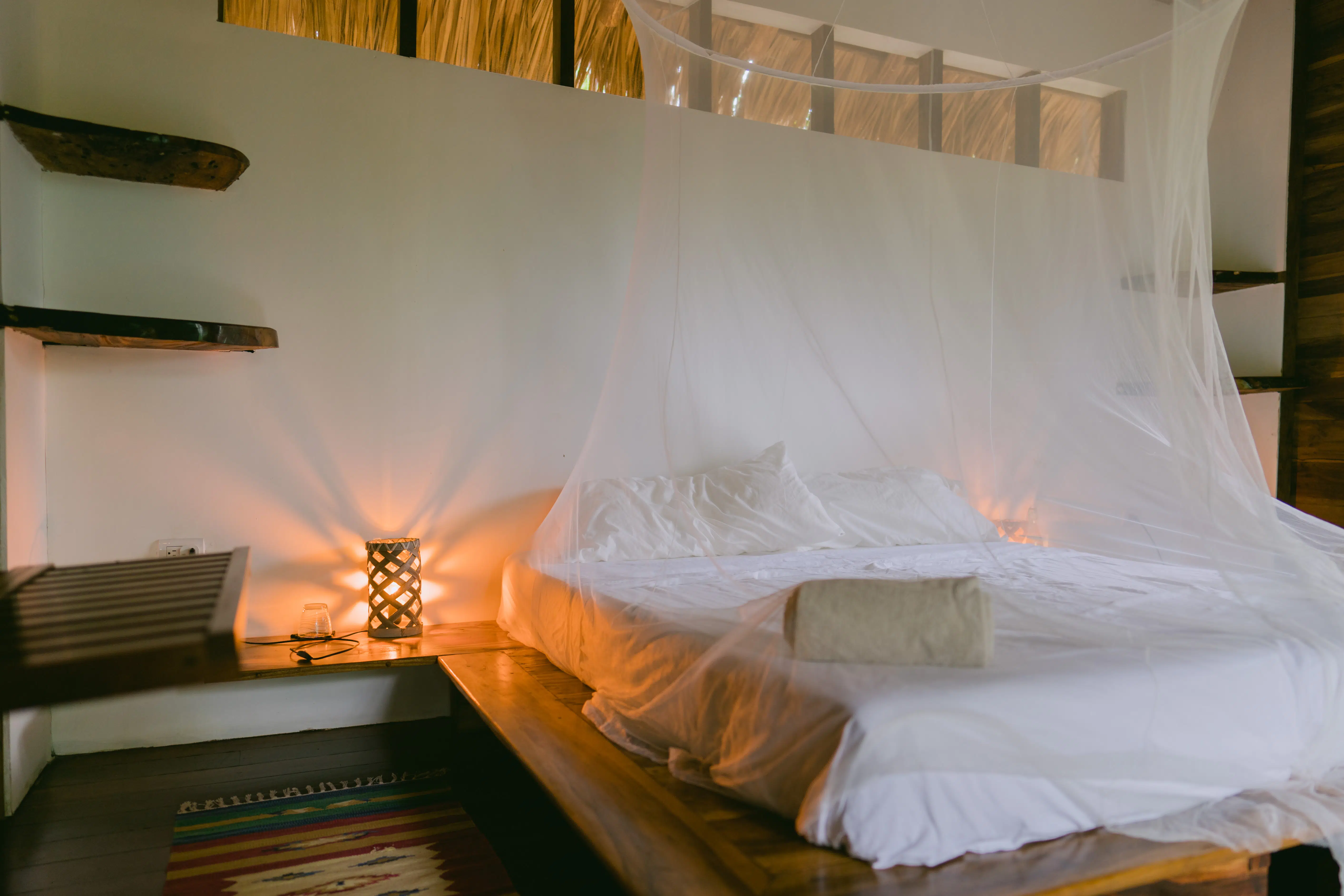 A bed with mosquito net on the cabana room in Rapture Surf resort