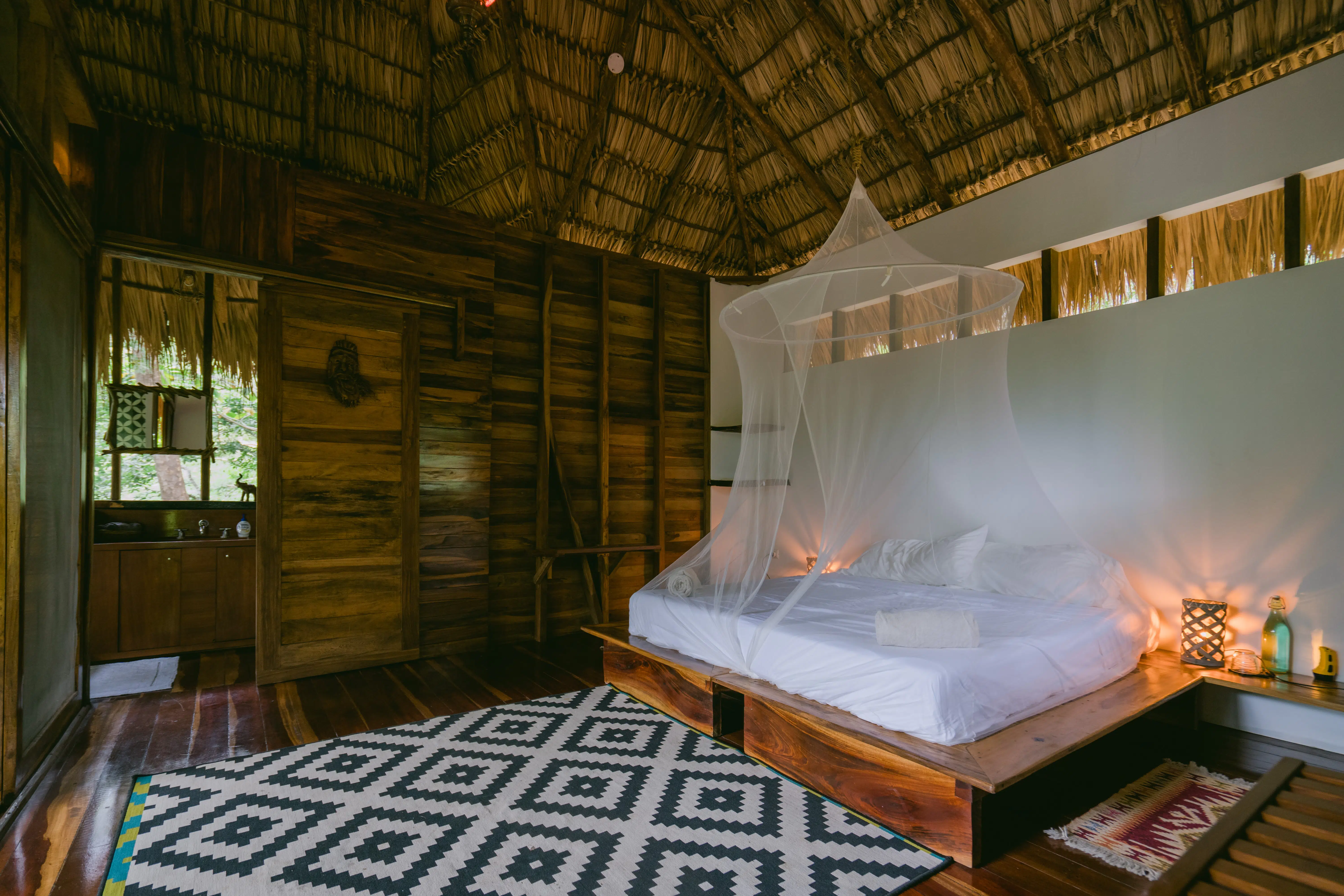 A bed with mosquito net on the cabana room in Rapture Surf resort