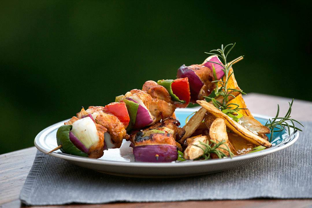 A plate of chargrilled chicken kebabs with potatoes and rosemary