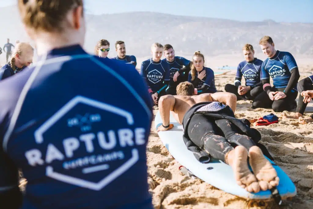 Surfcoach erklärt Surfschülern den Pop Up am strand