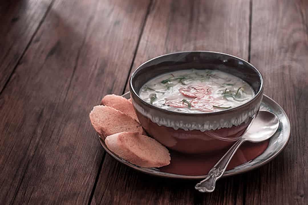 A Bowl of borecole soup with bread on the side