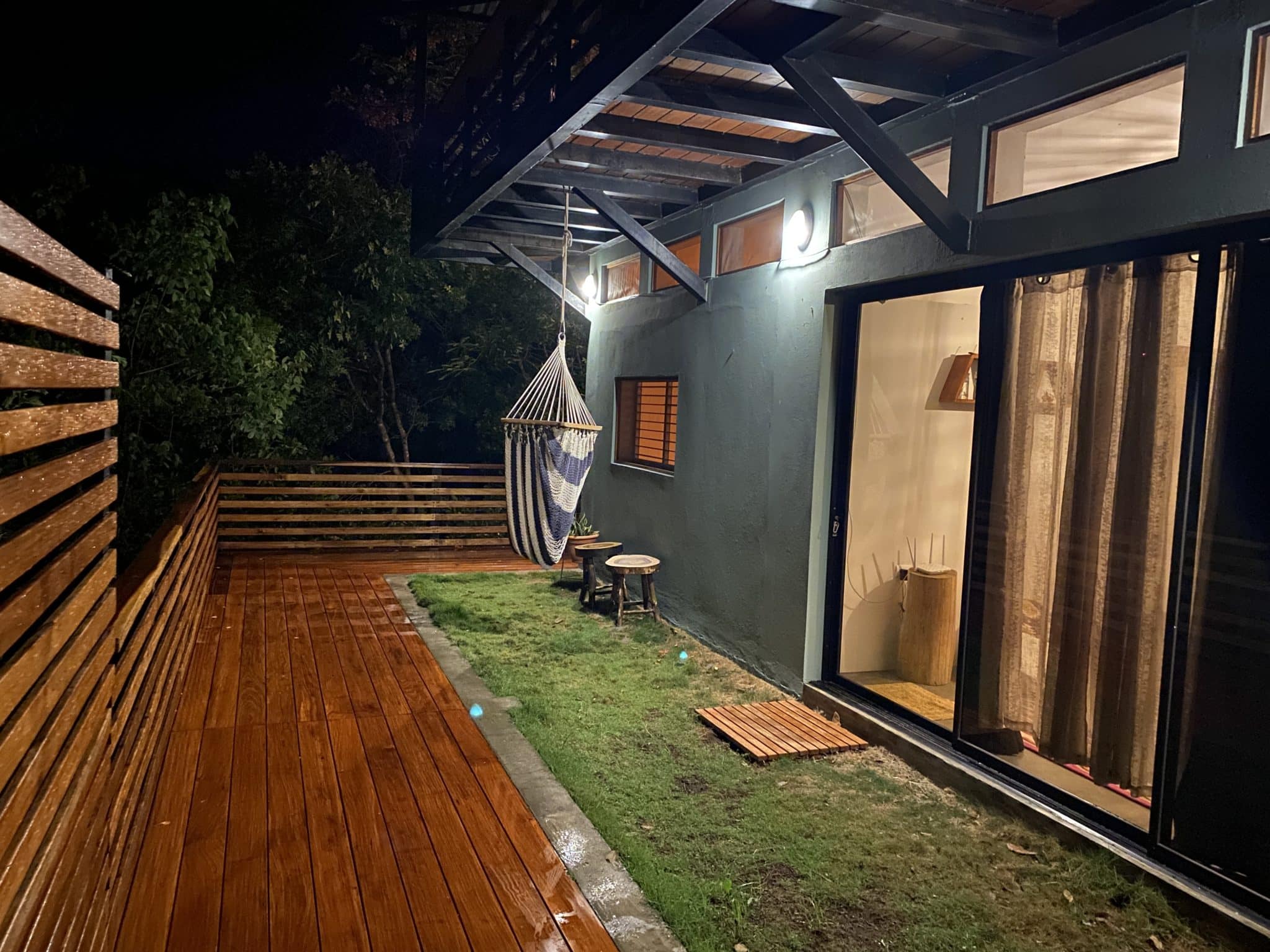 A pateo of wooden deck with grass and hammock chair
