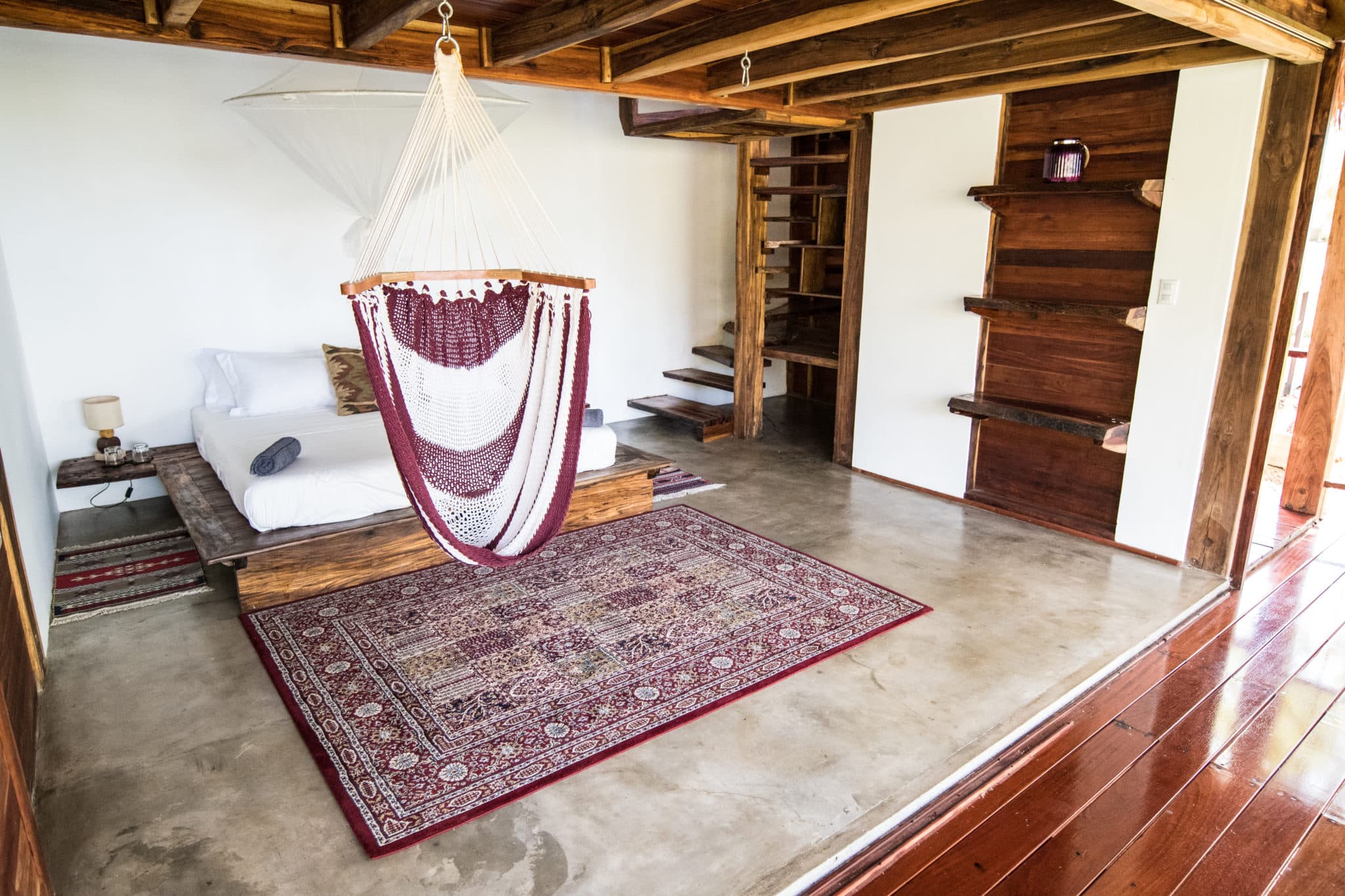 A spacious and luxurious room with a bed and hammock chair
