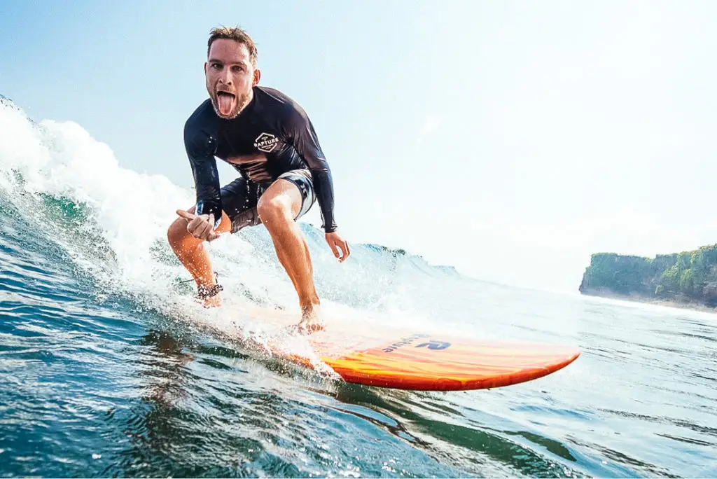 A happy surfer riding wave in Bali beach