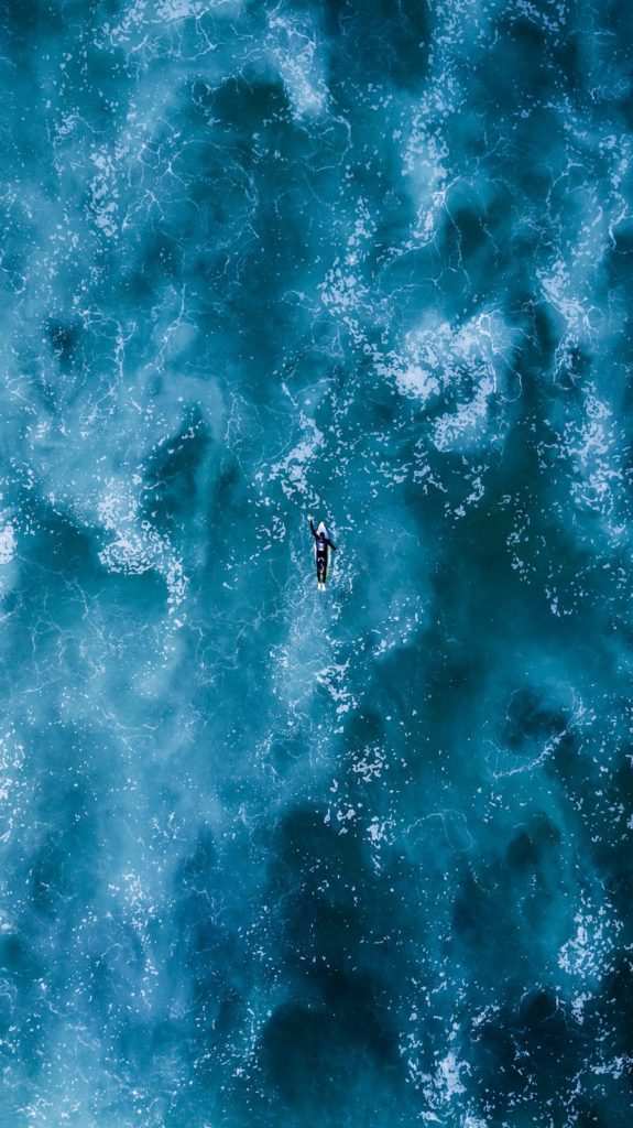 Surfer paddling out some waves