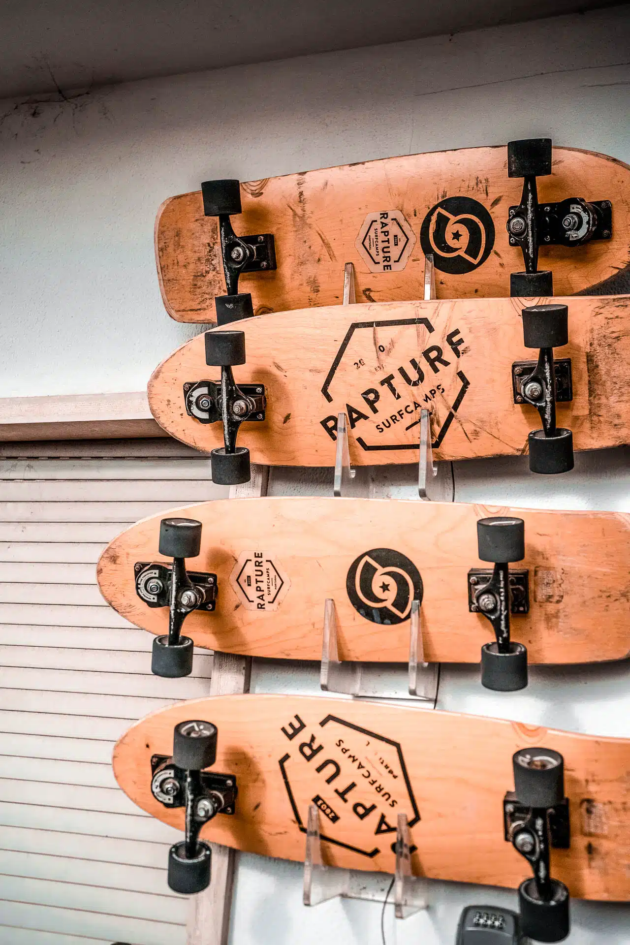 Skateboard with Rapture Surfcamps logo hanging on a wal.