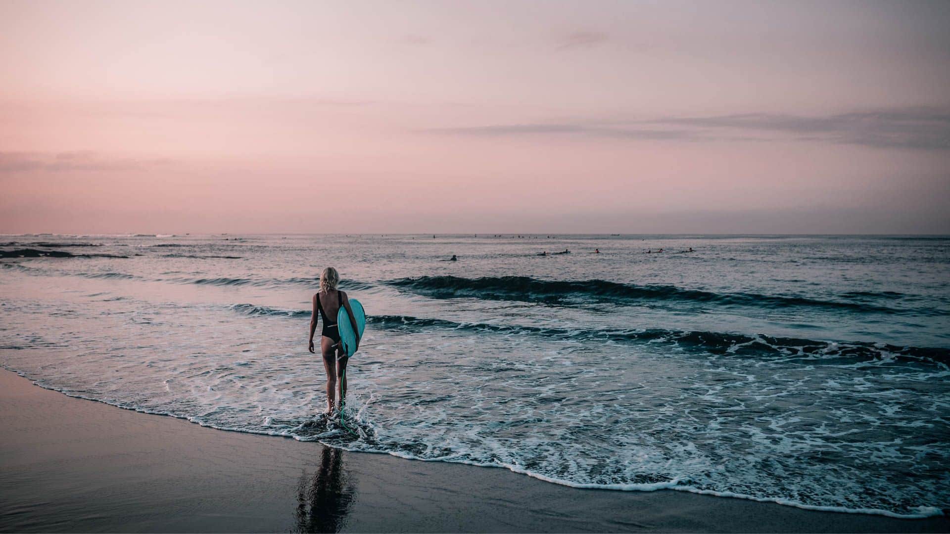 An image of a solo travelling surfer walking into the sea in portugal