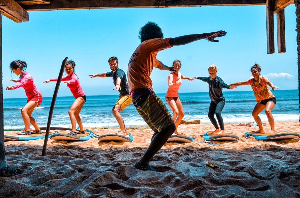 Surf Instructor teaching beginner surfers in the sand on the beach.