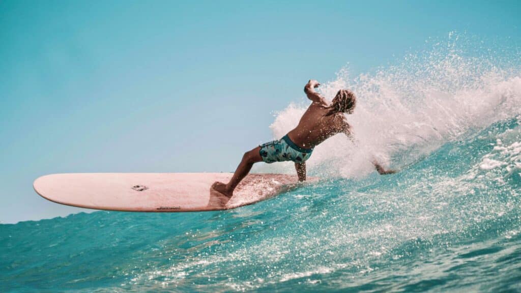 A surfer balancing on his board whilst riding a wave he has long blonde hair