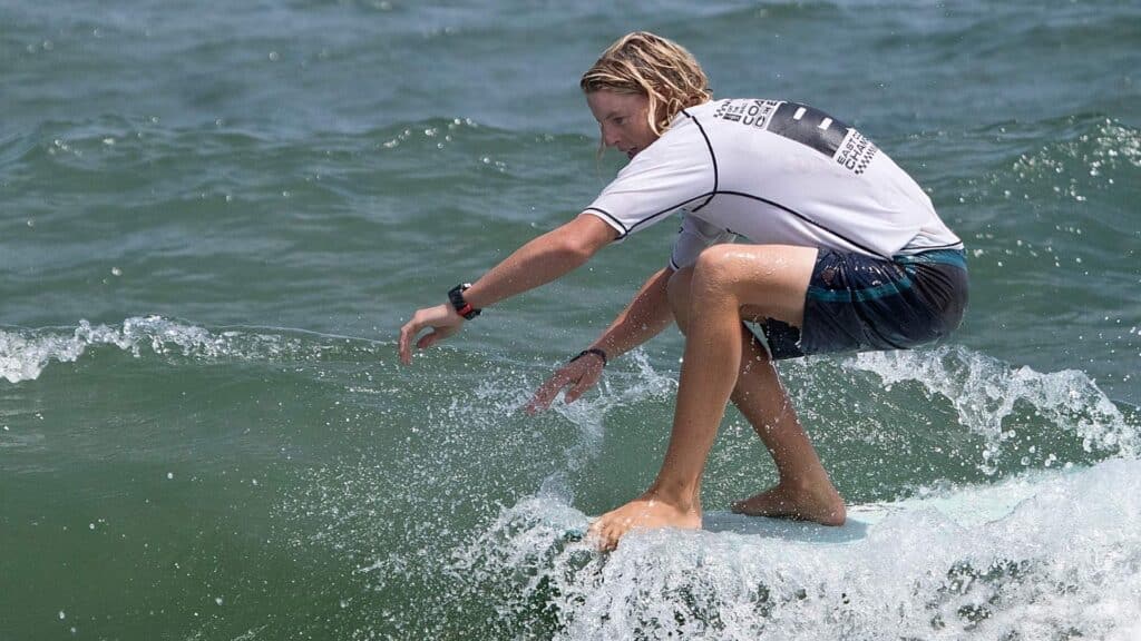 An image of a female surfer performing a hang 10 on a surfboard