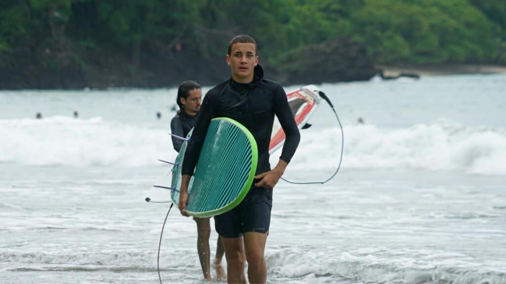 An image of a surfer holding a surfboard in the rain in Costa Rica