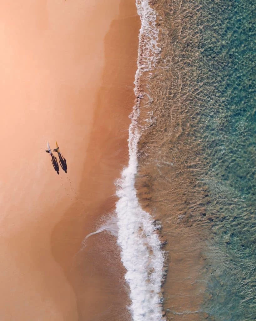 Two surfers walking down beach