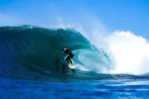A person surfing on a wave in Ericeira, on blue waters.
